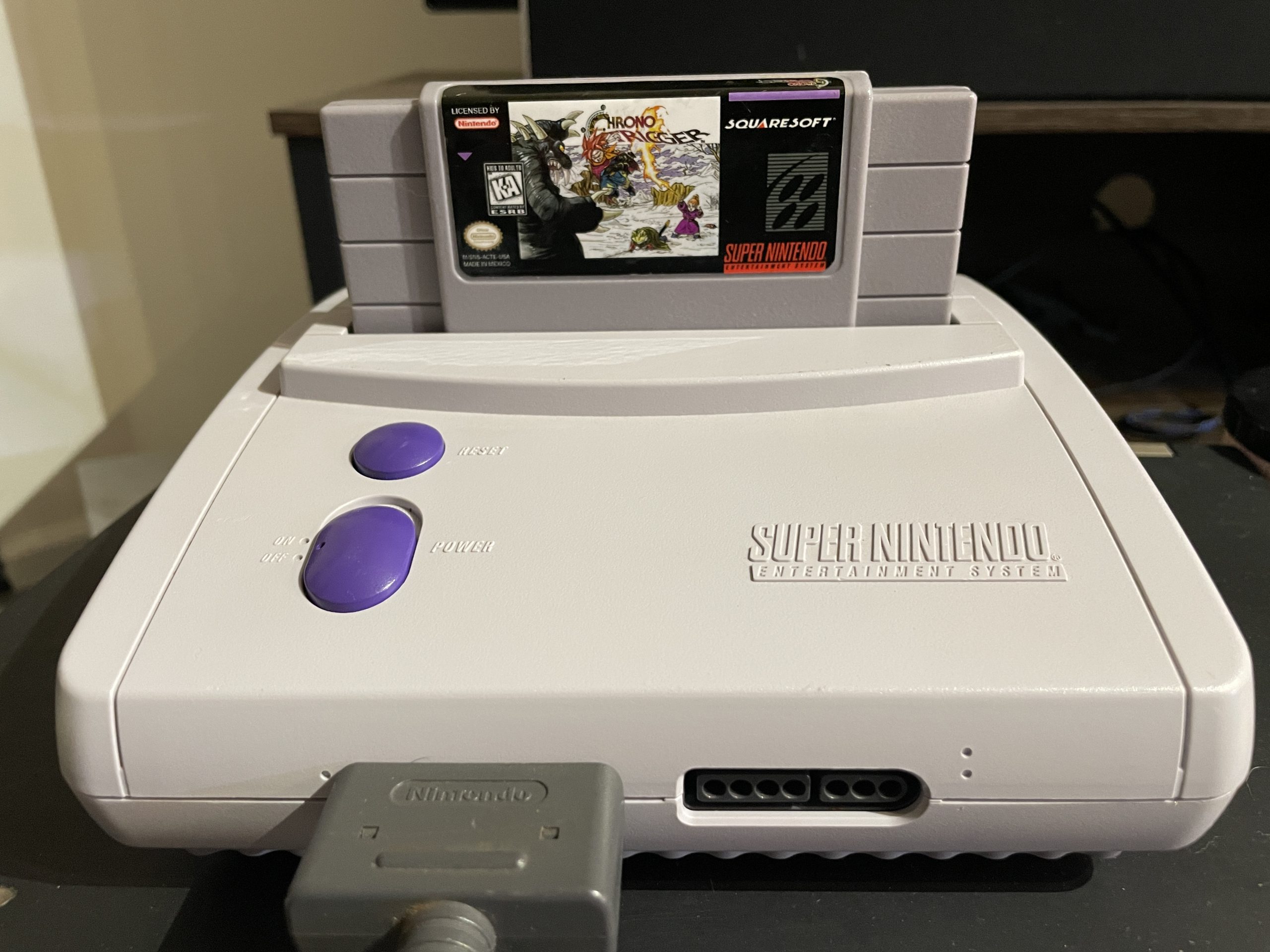 A front shot of the SNES Jr. with a controller connected and a Chrono Trigger cartridge inserted.